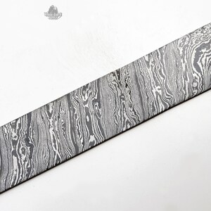 May include: A long, rectangular piece of metal with a wavy, patterned surface. The metal has a silver and gray color.