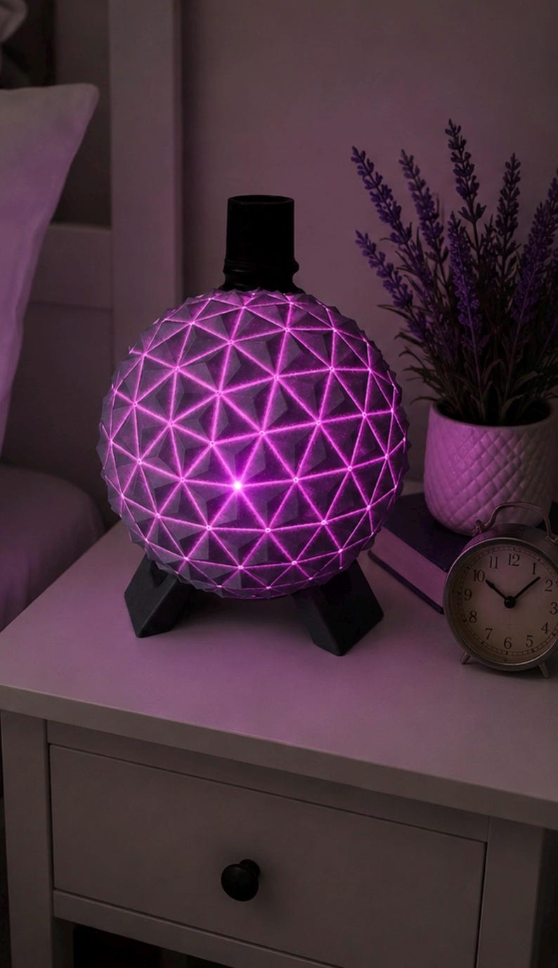 May include: A spherical lamp featuring a geometric geodesic dome pattern with a vibrant pink light emanating from the crevices. The lamp is supported by a black tripod base and has a black cylindrical top component, creating a modern lighting fixture.