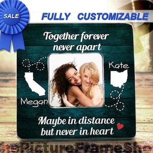 K&ouml;nnte beinhalten: Ein quadratischer Bilderrahmen mit dunkelblau-gr&uuml;nem Holzmaserungshintergrund. Er zeigt den Text Together forever never apart und Maybe in distance but never in heart. Enth&auml;lt wei&szlig;e Silhouetten von Kalifornien und Ohio mit Linien.