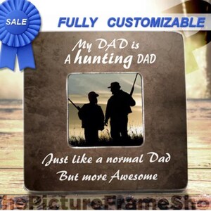 May include: A brown picture frame with a silver border and a photo of two people hunting. The frame has the text "My DAD is A hunting DAD Just like a normal Dad But more Awesome" on it.