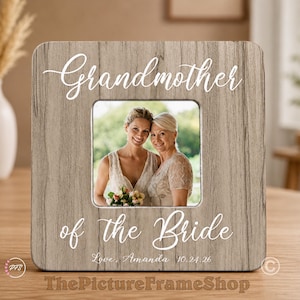 May include: A square wooden picture frame with a light brown wood grain finish. The frame features white script text that reads Grandmother of the Bride, with the additional text Love, Amanda 10.24.26. A photo of two people is displayed.