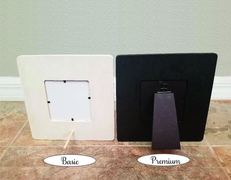 Pode incluir: Duas molduras para fotos, uma branca e outra preta, ambas com um passe-partout branco e uma frente de vidro transparente. A moldura branca tem um simples suporte de madeira, enquanto a moldura preta tem um suporte preto mais robusto. A moldura branca &eacute; etiquetada como "B&aacute;sica" e a moldura preta como "Premium".