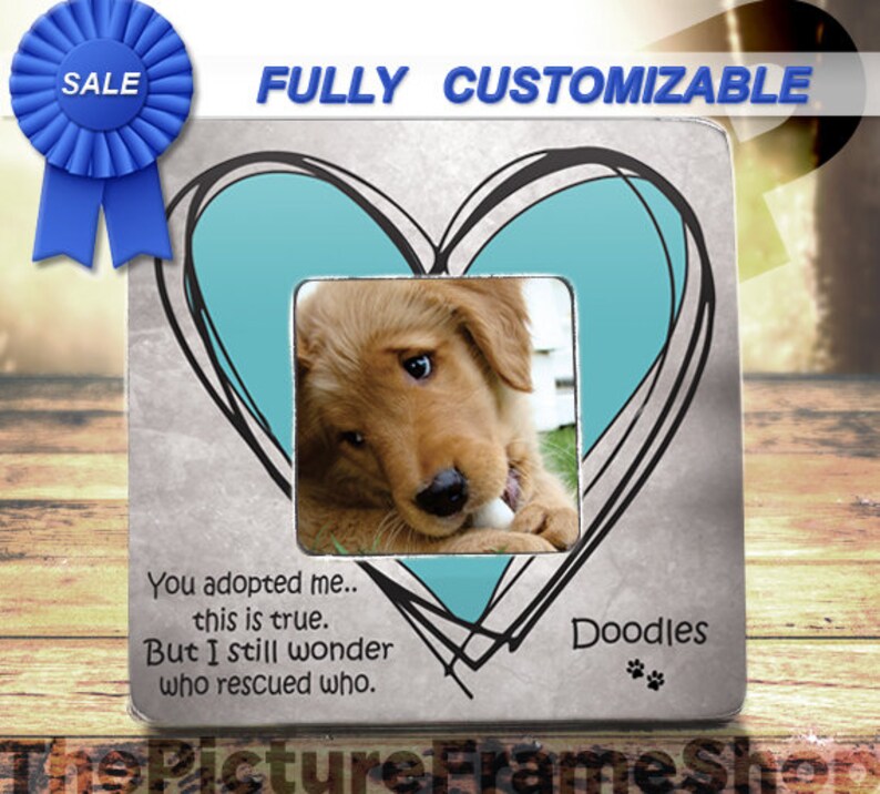 May include: A silver picture frame with a blue heart design and a photo of a golden retriever puppy. The frame has the text "You adopted me... this is true. But I still wonder who rescued who." and "Doodles" with paw prints.