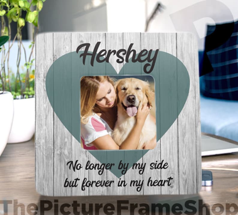 Pode incluir: Uma moldura de madeira com um recorte em forma de cora&ccedil;&atilde;o e uma foto de uma mulher e seu c&atilde;o. A moldura tem o texto "Hershey" no topo e "No longer by my side but forever in my heart" na parte inferior.
