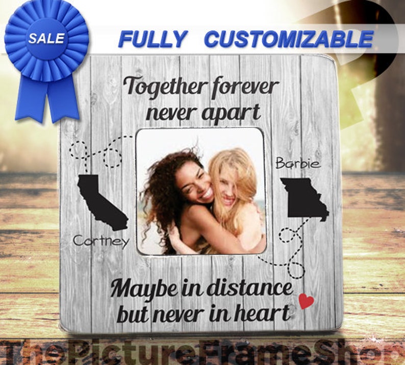 K&ouml;nnte beinhalten: Ein quadratischer Bilderrahmen mit grauer Holzmaserung und dem Text Together forever never apart sowie Maybe in distance but never in heart. Er enth&auml;lt schwarze Silhouetten von Kalifornien und Missouri mit gestrichelten Linien.