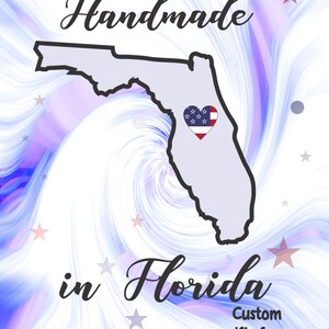 May include: A graphic design featuring the outline of Florida in light gray, with a heart-shaped emblem colored with the American flag. The words "Handmade in Florida" are written in a script font, with the text "Custom gifts from The HEART!" below.