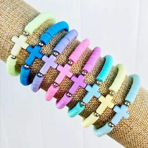 May include: A stack of colorful beaded bracelets with silver cross charms. The bracelets are in shades of blue, green, yellow, pink, and purple.