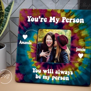 May include: Square photo frame with a tie-dye design in shades of blue, pink, and yellow. The frame features the text "You're My Person" and "You will always be my person." A photo of two women is in the center.