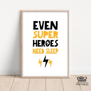 May include: A printable wall art design with the text "Even Super Heroes Need Sleep" in black with yellow lightning bolts. The design is on a white background with a wood frame.