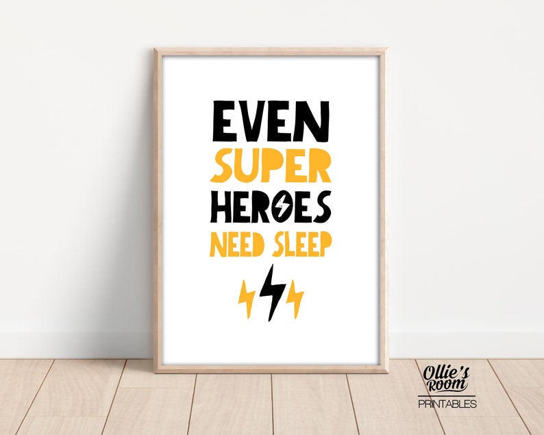 May include: A printable wall art design with the text "Even Super Heroes Need Sleep" in black with yellow lightning bolts. The design is on a white background with a wood frame.