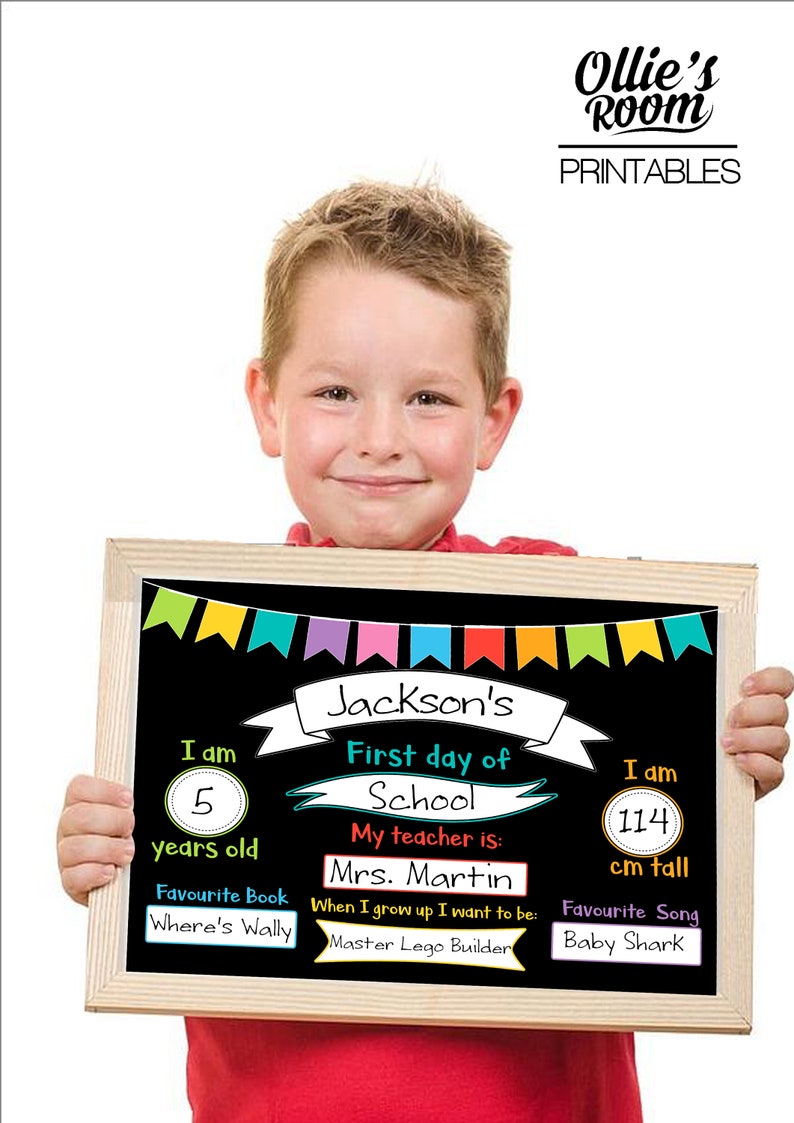 May include: A wooden framed chalkboard sign with the text "Jackson's First day of School". The sign includes the child's age, height (114 cm), favorite book, teacher's name, and favorite song. The sign is decorated with colorful bunting.