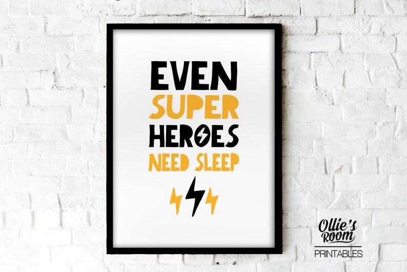 May include: Black and yellow printable wall art with the text "Even Super Heroes Need Sleep" and two lightning bolts. The art is framed in a black frame and is hanging on a white brick wall. The text "Ollie's Room Printables" is in the bottom right corner.