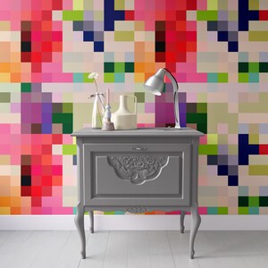 Puede incluir: Un armario de madera gris con tallas ornamentadas y un solo caj&oacute;n. El armario est&aacute; delante de una pared con un patr&oacute;n pixelado de colores.