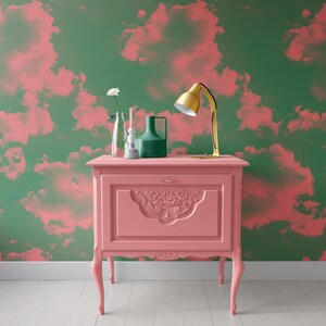 Puede incluir: Una mesa auxiliar antigua pintada de rosa con tallas ornamentadas y detalles dorados. La mesa tiene tres patas y est&aacute; decorada con una l&aacute;mpara, un jarr&oacute;n y una flor.
