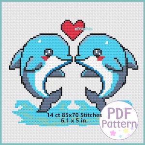 May include: A cross-stitch pattern featuring two blue dolphins facing each other, with a red heart above them. The dolphins are on a blue wave, and the pattern is 6.1 x 5 inches.