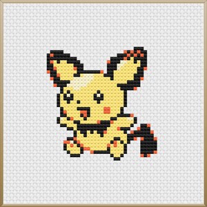May include: A cross-stitch of a yellow cartoon character with black outlines, orange cheeks, and a black and orange tail. The character has large ears and is set against a white background within a wooden frame. The character is smiling with its tongue out.
