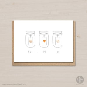 Pode incluir: Um cartão com três frascos de vidro, cada um com uma etiqueta com um símbolo: sinal de paz, coração e smiley. As palavras "PEACE . LOVE . JOY" estão abaixo dos frascos. O cartão está em um fundo marrom.