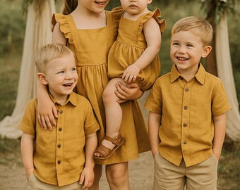 Puede incluir: Un grupo de niños con conjuntos a juego de color mostaza, incluyendo vestidos, camisas abotonadas, pantalones cortos y sandalias. Los niños están de pie frente a un arco decorativo, con telas similares al lino.