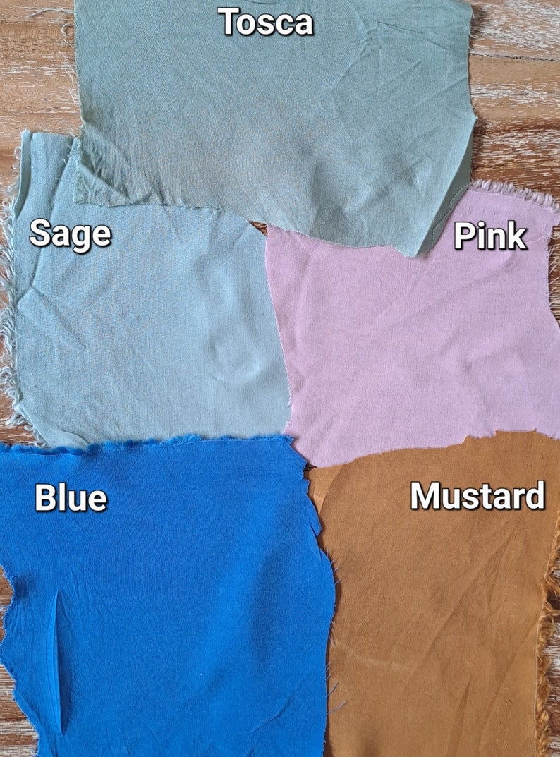 Puede incluir: Muestras de tela en tonos Tosca, Salvia, Rosa, Azul y Mostaza, cada una con un borde sin rematar. Los nombres de los colores est&aacute;n en la tela. Las muestras est&aacute;n dispuestas sobre una superficie de madera, mostrando los colores.
