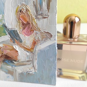 May include: A painting of a woman reading a book in a white room with a window. The painting is done in a loose, impressionistic style with thick brushstrokes. The woman is wearing a white shirt and has blonde hair. The painting is framed and has a light blue background.