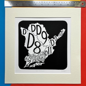 May include: A black and white linocut print of a map of the United Kingdom with the text "DD Postcodes" and "PLEAS" at the bottom.