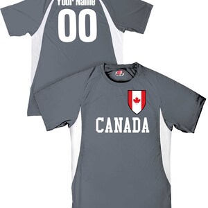 May include: Gray athletic jersey with white accents and the word "CANADA" in white block letters. A shield with a red maple leaf is above the word. The back of the jersey has the text "Your Name" and the number "00".