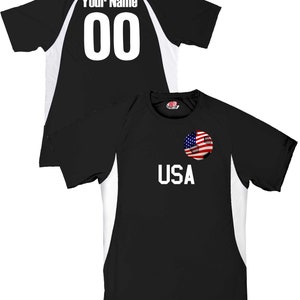May include: Black soccer jersey with white accents and a soccer ball with an American flag design. The jersey has the text "USA" on the front and "Your Name 00" on the back.