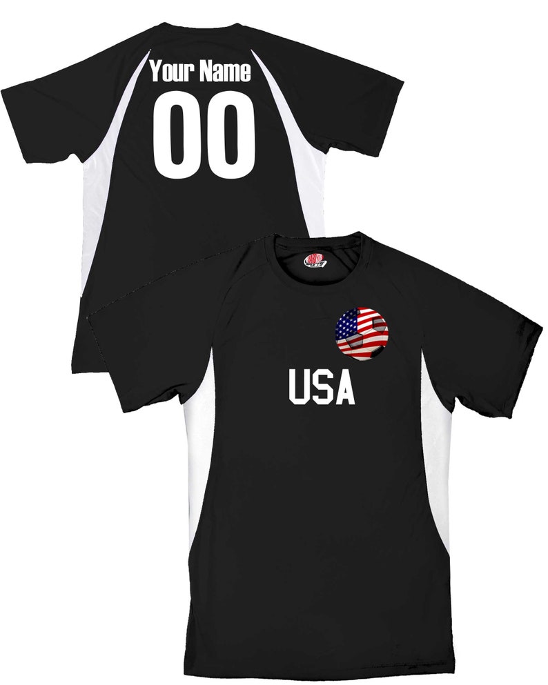 May include: Black soccer jersey with white accents and a soccer ball with an American flag design. The jersey has the text "USA" on the front and "Your Name 00" on the back.