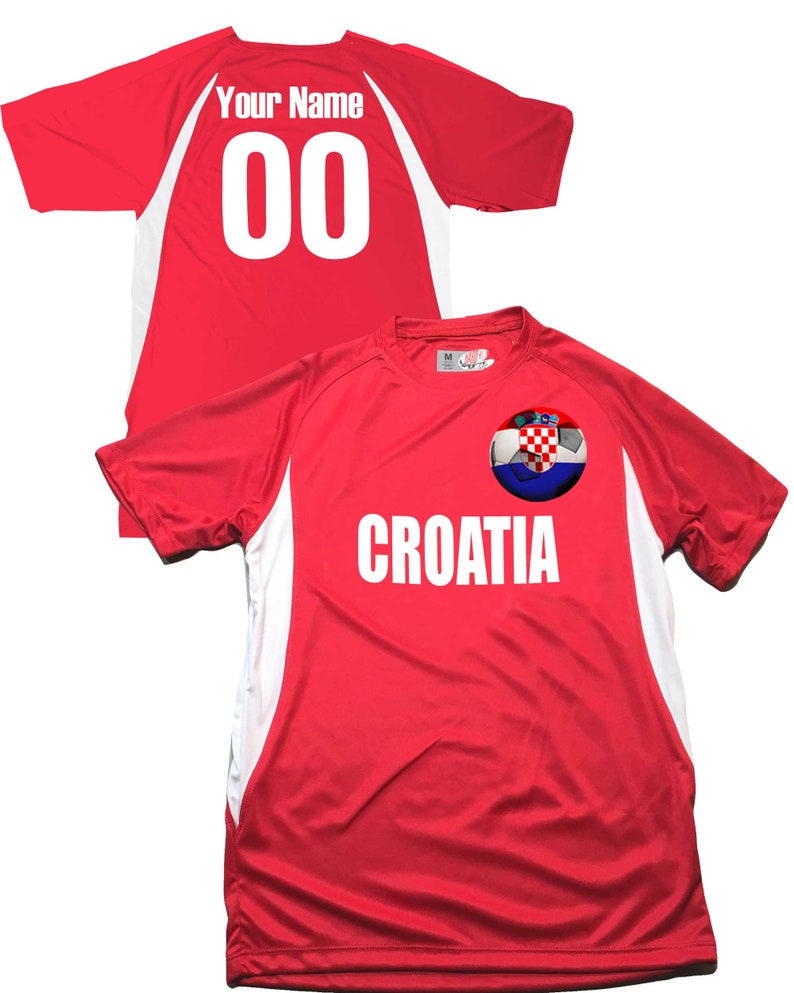 Puede incluir: Camiseta de f&uacute;tbol roja con detalles blancos y un bal&oacute;n de f&uacute;tbol con la bandera croata en la parte delantera. La camiseta tiene la palabra "CROATIA" impresa en la parte delantera y el n&uacute;mero "00" en la parte posterior.