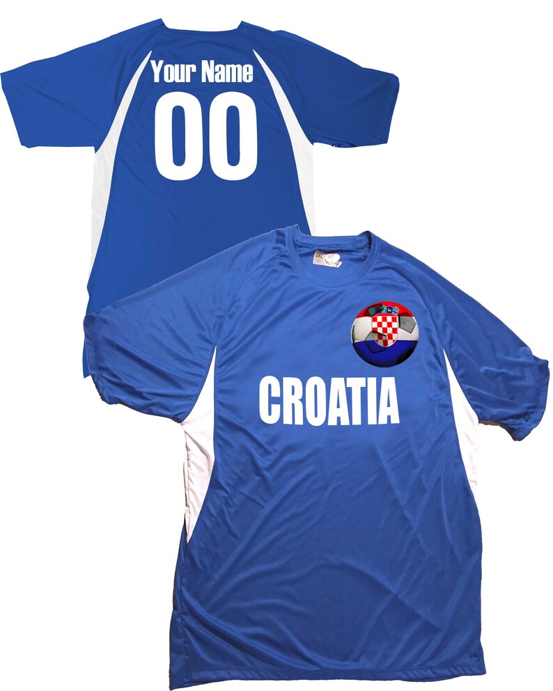 Puede incluir: Una camiseta de f&uacute;tbol azul con detalles blancos y el texto "CROATIA" en la parte delantera. La camiseta presenta un bal&oacute;n de f&uacute;tbol con la bandera croata en &eacute;l. La parte posterior de la camiseta tiene el texto "Your Name" y el n&uacute;mero "00" en blanco.