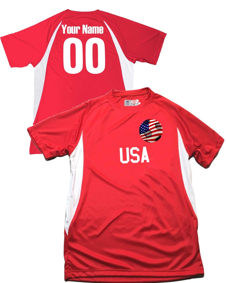 May include: Red soccer jersey with white accents and the word "USA" on the front. A soccer ball with the American flag is on the chest. The back of the jersey has the text "Your Name" and the number "00" in white.