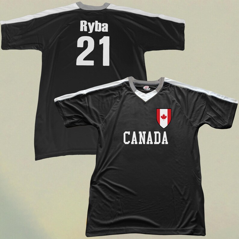 May include: Black football jersey with white shoulder and sleeve detailing. The jersey displays the word "CANADA" in white, a Canadian flag crest, and the name "Ryba" and number "21" on the back.