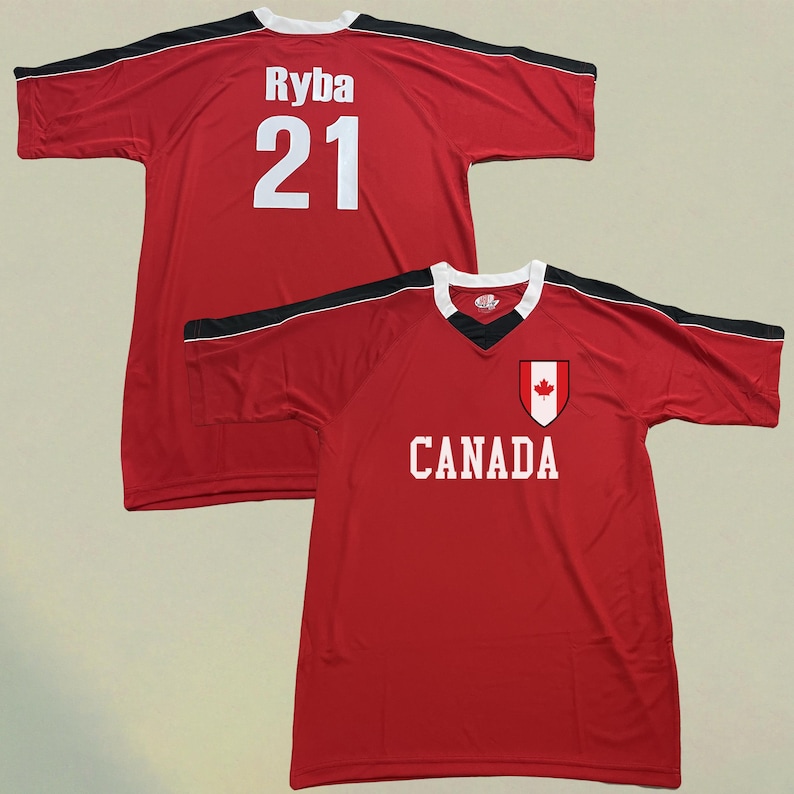 May include: Red jersey with black and white detailing. The jersey has the name "Ryba" and the number "21" in white on the back. The front of the jersey shows the word "CANADA" and a Canadian flag emblem.