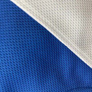 May include: Close-up of a blue and white athletic fabric. The blue fabric is a vibrant royal blue, and the white fabric is a crisp, clean white. Both fabrics have a textured, breathable weave, suggesting a performance material.
