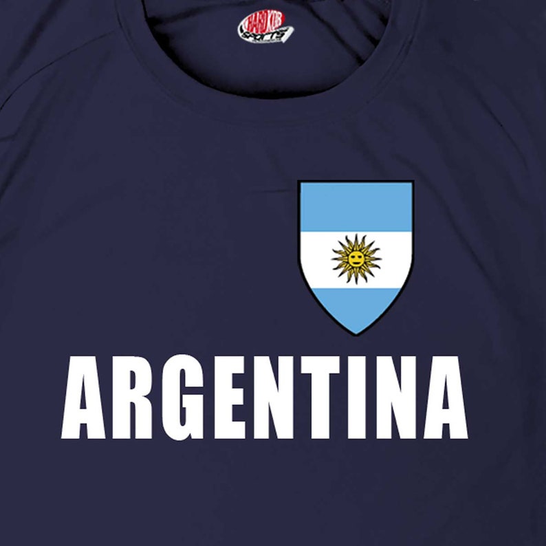 May include: A navy blue t-shirt with a white "ARGENTINA" text and a white and light blue shield with the Argentine flag inside.