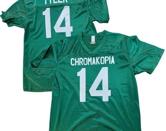 May include: Two green mesh football jerseys. One jersey has "TYLER" and the number "14" in white on the back. The other jersey has "CHROMAKOPIA" and the number "14" in white on the front.
