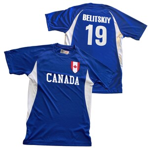 May include: Two blue athletic jerseys. One jersey has the name "BELITSKIY" and the number "19" on the back. The other jersey has the word "CANADA" and a maple leaf emblem on the front. Both jerseys have white accents.
