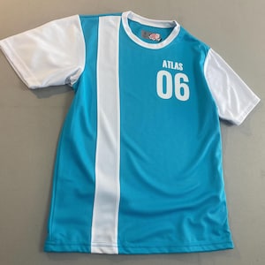 May include: A turquoise athletic jersey with white sleeves and a white vertical stripe down the front. The word "ATLAS" and the number "06" are printed in white on the front of the jersey. The jersey has a round neckline.