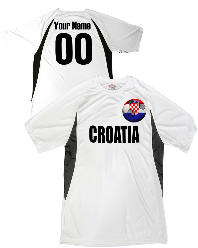Puede incluir: Camiseta de f&uacute;tbol blanca con detalles en negro y gris. La camiseta tiene un bal&oacute;n de f&uacute;tbol con la bandera croata y la palabra "CROATIA" impresa en la parte delantera. La parte posterior de la camiseta tiene un n&uacute;mero negro "00" y el texto "Your Name" impreso.