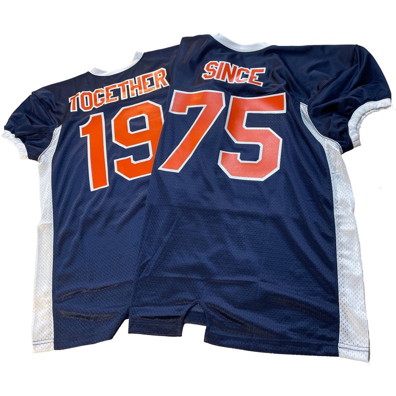 May include: Two navy blue mesh jerseys with white and orange lettering. One jersey reads "TOGETHER 1975" and the other reads "SINCE 1975". The jerseys have white trim on the sleeves and sides.