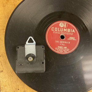 May include: A black vinyl record with a red label. The label has the text "Columbia" in white letters and the text "The Mermaid" in white letters. The record is 39862 (RHCO 10235) and features Frankie Laine with Paul Weston & his Orch. & The Norman Lubeff Choir. Carl Fischer - Piano.