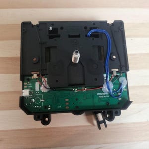 May include: A black electronic component with a green circuit board, wires, and a silver metal piece. Blue wires are attached to the green board. The text "203688" and "2022.01.03" are printed on the board.