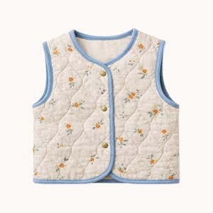 Könnte beinhalten: Eine ärmellose, gesteppte Weste aus hellbeigem Stoff mit einem kleinen orangefarbenen Blumenmuster und grünen Blättern. Die Weste hat eine blaue Stoffeinfassung an den Kanten und einen Verschluss mit drei goldfarbenen Metalldruckknöpfen.