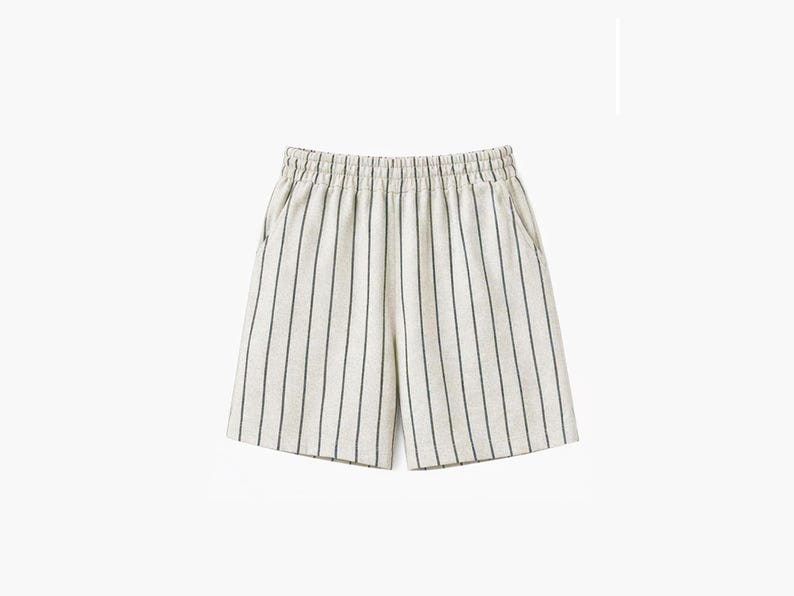 May include: Off-white shorts featuring a vertical pinstripe pattern in a dark charcoal color. These shorts have an elasticized waistband with gathered fabric detailing and two side pockets, providing a clean and functional design.