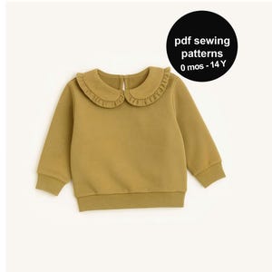 May include: Mustard-colored long-sleeved sweatshirt with a ruffled collar. The garment has a round neckline and ribbed cuffs and hem. A black circle in the upper right corner reads "pdf sewing patterns 0 mos - 14 Y".