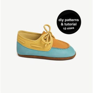 May include: A colorful baby shoe in shades of yellow, orange, and blue. The shoe has a classic boat shoe design with laces and a stitched construction. The image includes a black circle with the text "diy patterns & tutorial 10 sizes".