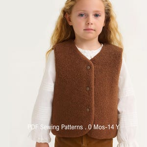 Könnte beinhalten: Eine braune ärmellose Weste mit strukturierter Fleece-Optik und drei Druckknöpfen auf der Vorderseite. Das Kleidungsstück wird über einem weißen langärmeligen Hemd mit gerüschten Manschetten getragen. Der Text PDF Sewing Patterns . 0 Mos-14 Y ist unten sichtbar.