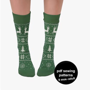Puede incluir: Calcetines altos verdes con un patrón nórdico blanco con renos, copos de nieve y árboles de Navidad. Los calcetines tienen un puño verde oscuro y están diseñados para 9 meses a adultos. La imagen incluye un círculo negro con texto.