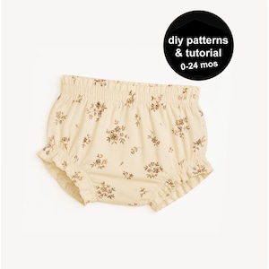 Könnte beinhalten: Cremefarbene Baby-Bloomers mit einem floralen Muster in Brauntönen. Die Bloomers haben einen gerüschten Rand und einen elastischen Bund. Das Bild enthält auch einen schwarzen Kreis mit dem Text "diy patterns & tutorial 0-24 mos."