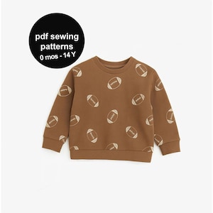 May include: Brown sweatshirt with a repeating pattern of footballs. The text "pdf sewing patterns 0 mos - 14 Y" is in a black circle in the upper left corner. The sweatshirt has a crew neck and long sleeves.